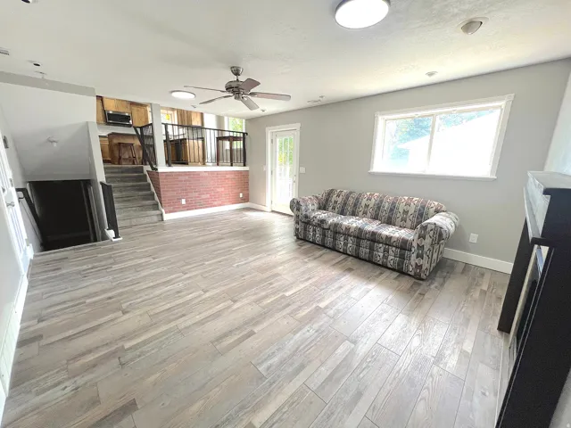 Spacious room featuring wood-finish flooring, a ceiling fan, and a large window
