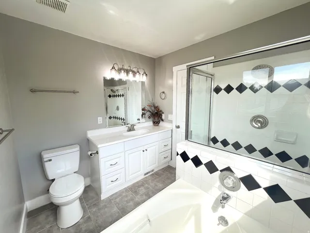 White vanity with dual sinks, a large mirror, and overhead lighting