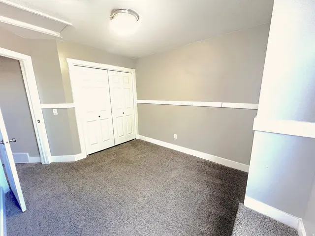 Neutral wall paint with chair rail molding, plush carpet flooring, bi-fold closet doors, and flush mount lighting