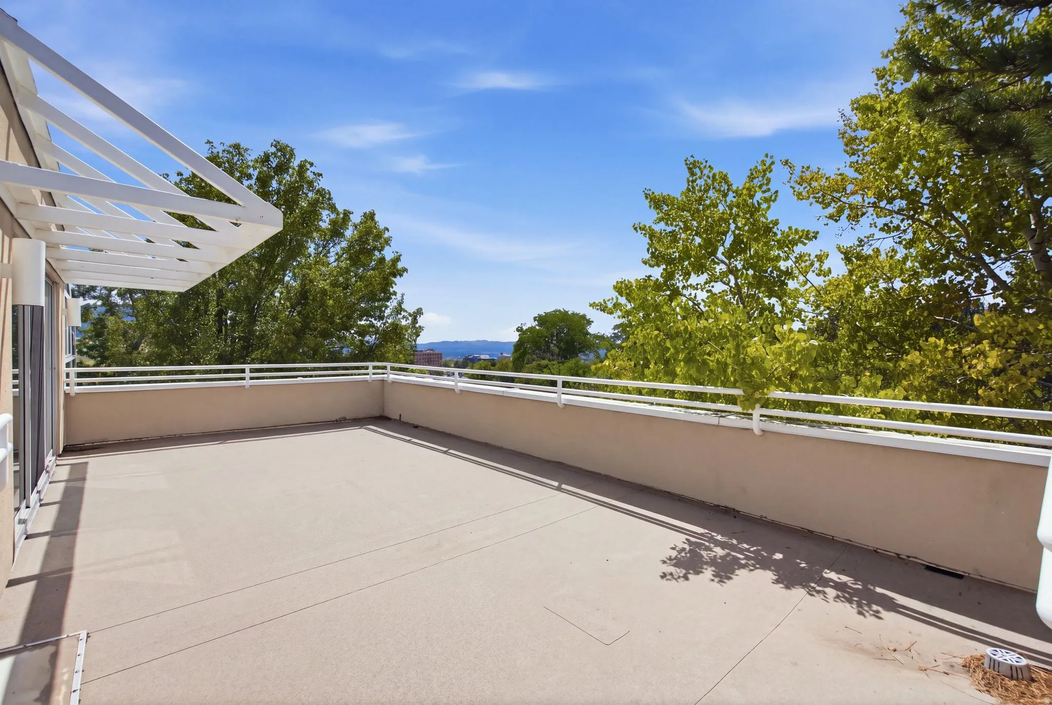Expansive outdoor terrace with a painted concrete surface, stucco half-wall, and white metal railing