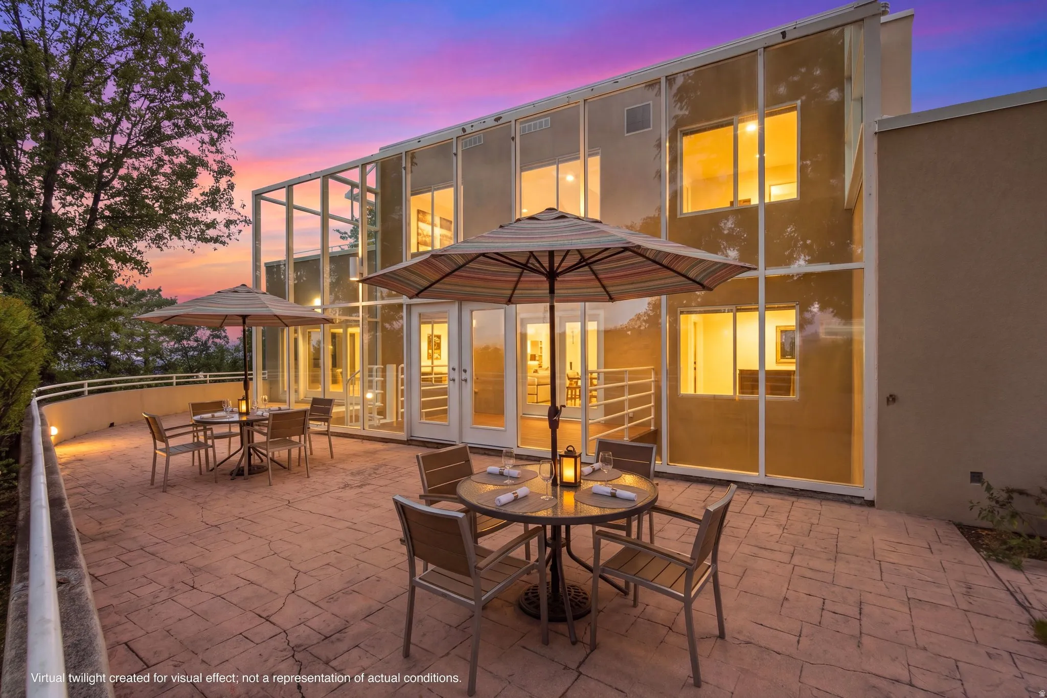 Expansive stamped concrete patio with architectural glass facade, multiple French doors, and exterior lighting