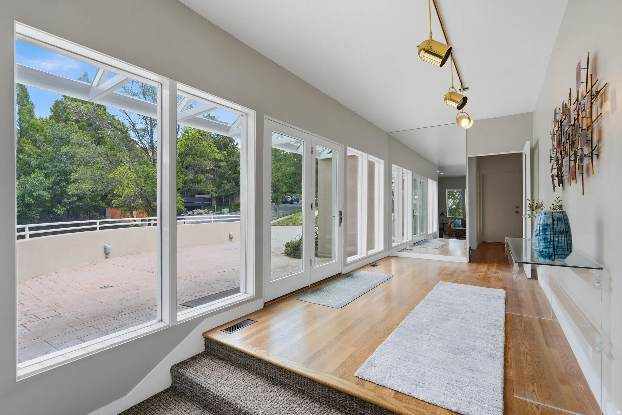 Sunlit sunroom with expansive multi-panel glass doors and windows overlooking manicured grounds