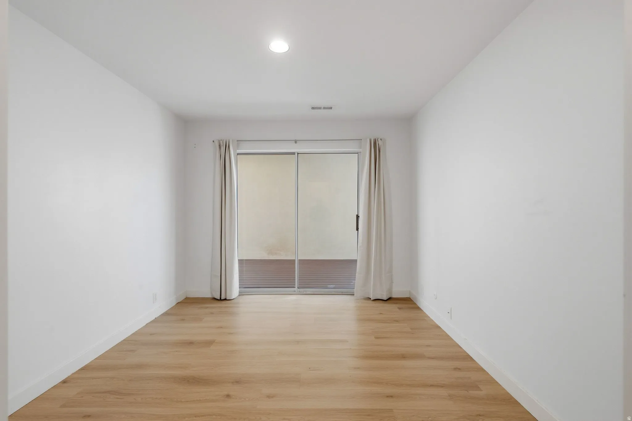 Recessed lighting, wood-finish flooring, white walls, and sliding glass doors