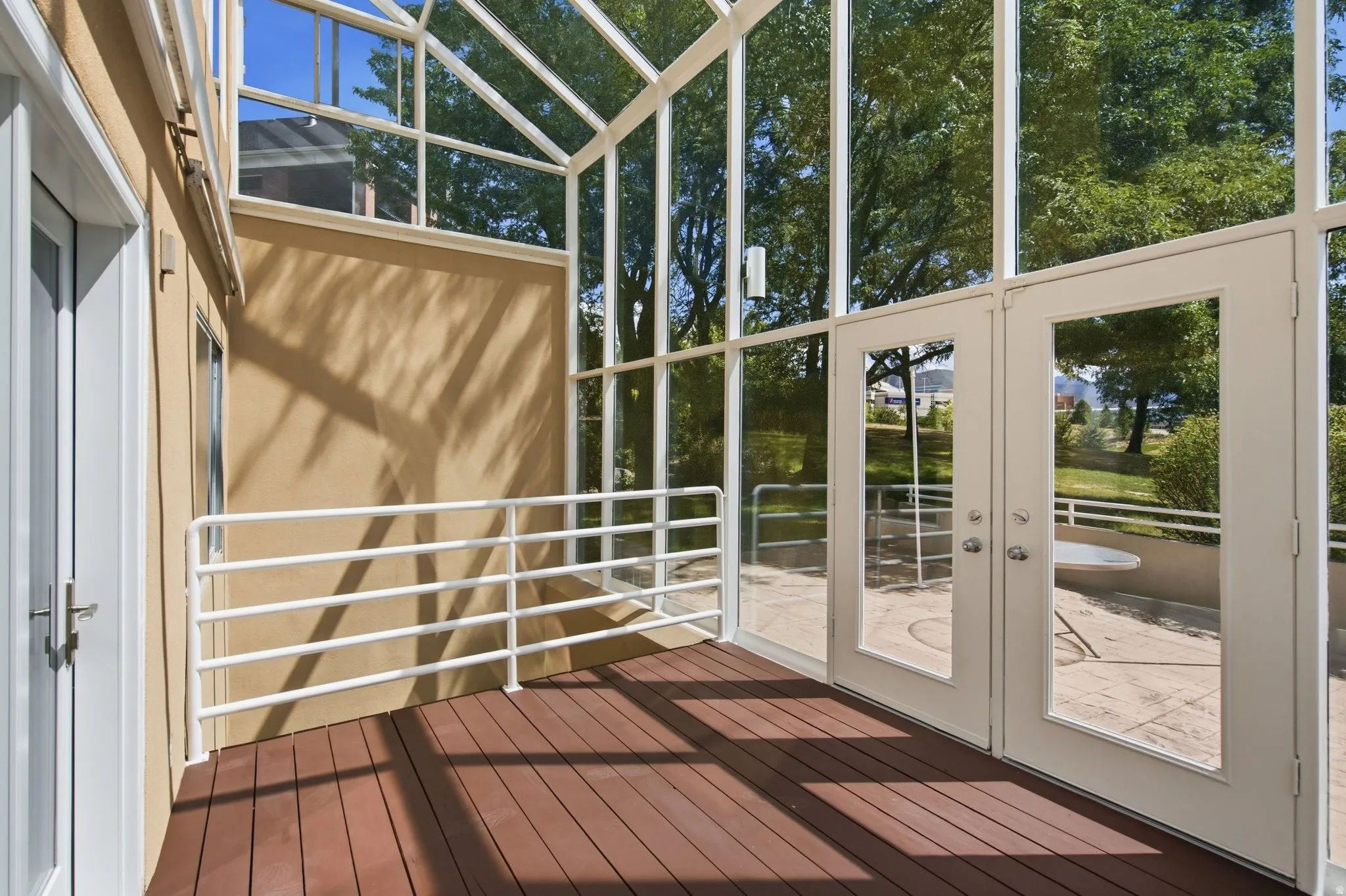 Expansive sunroom featuring a wood-finish floor, white railing, and full-height glass panels