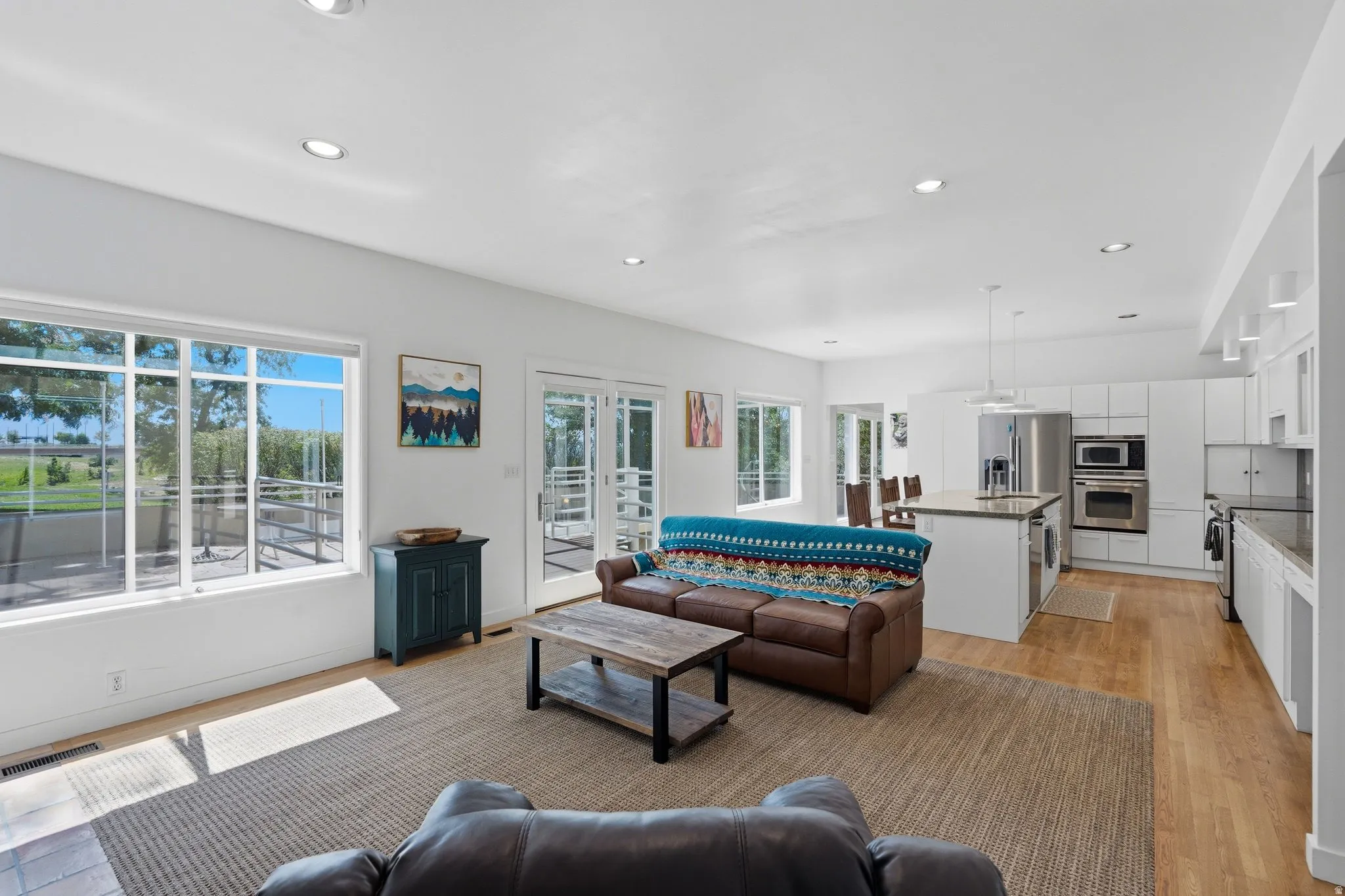 Open-concept living area with wood-finish flooring, recessed lighting, and large windows