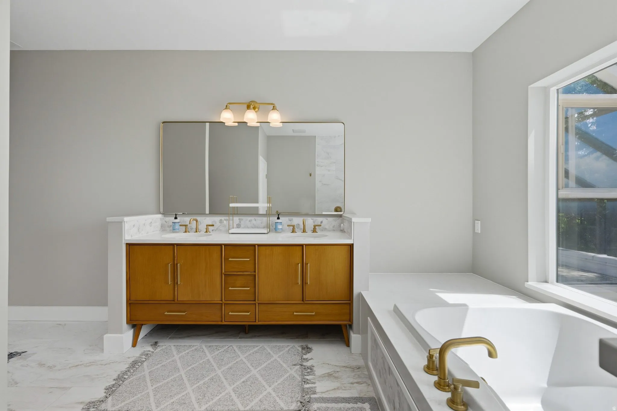 Dual vanity with wood-finish cabinetry, white countertop, and brass fixtures