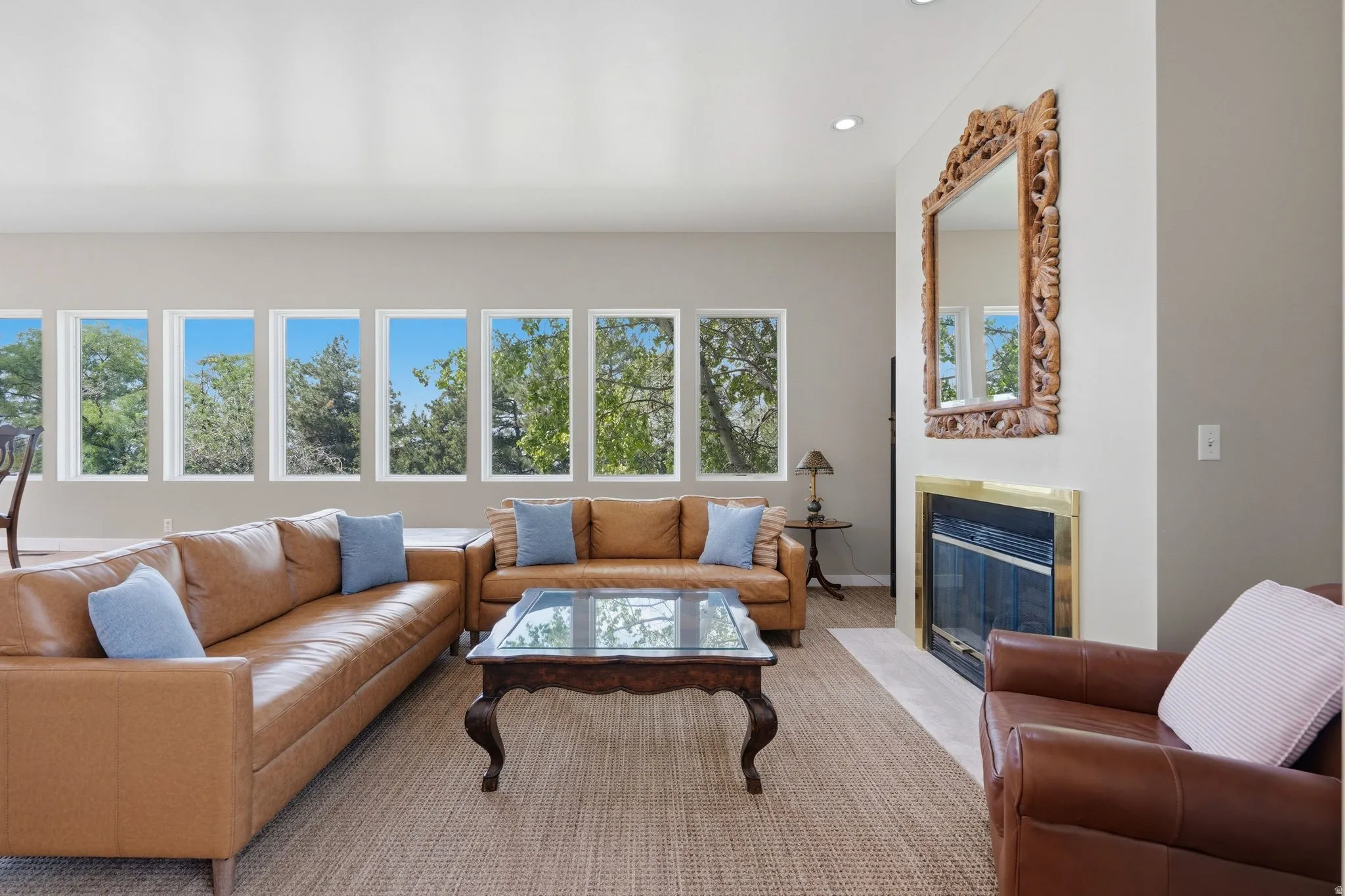 Recessed lighting, a fireplace with a brass-finish trim, and a series of multiple picture windows