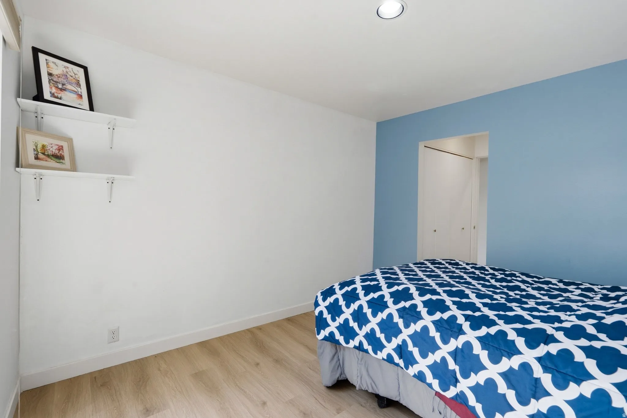 Recessed ceiling lighting, wood-finish flooring, built-in shelving, and bi-fold closet doors