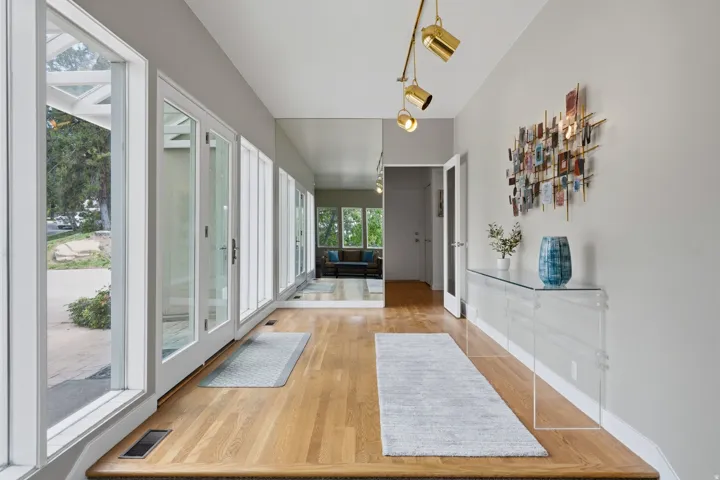 Hardwood flooring, full-length windows, track lighting fixture, and a built-in wall mirror