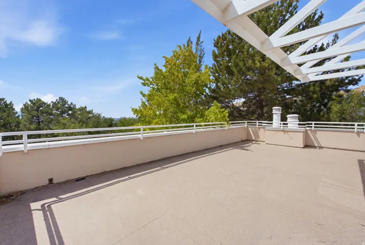 Rooftop deck featuring a white open-beam pergola, light-colored flooring, and a white perimeter railing