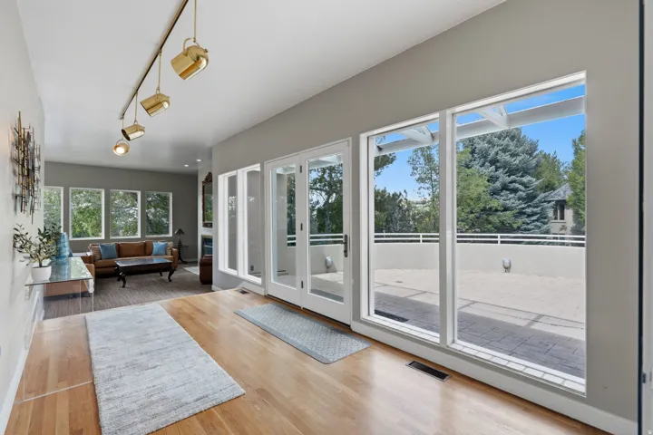 Hardwood-finish flooring, white-framed glass doors, large windows, track lighting fixtures, and a recessed ceiling