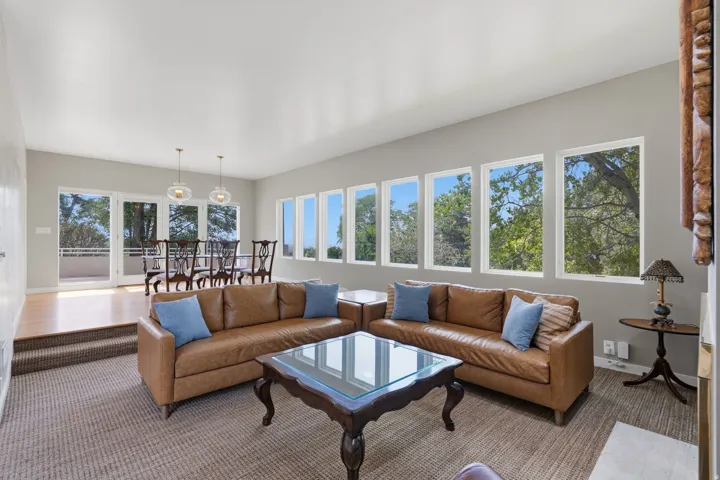 Carpeted living area with a series of rectangular windows, leading to a raised dining space with wood flooring