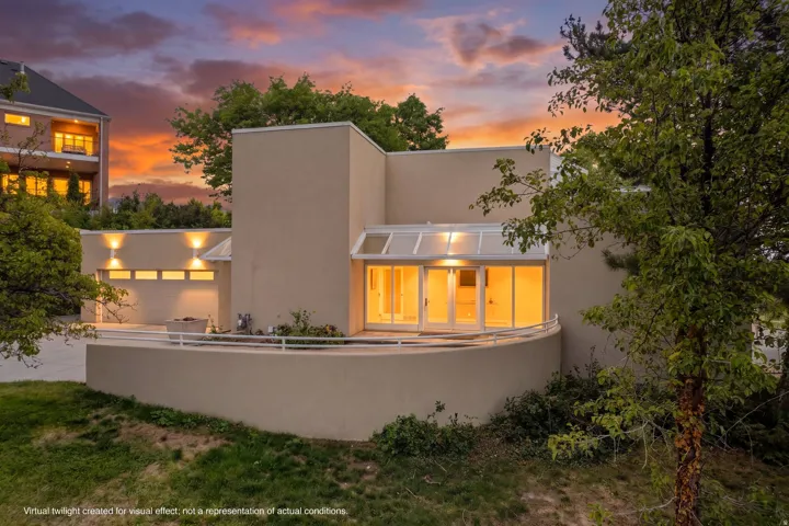 Contemporary architecture featuring a multi-level design, attached garage, and a curved balcony with white railing