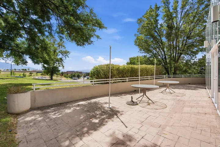 Expansive patio featuring paver hardscaping, mature shade trees, and open sightlines across manicured grounds