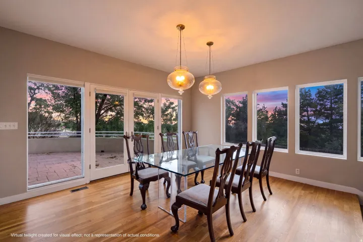 Hardwood flooring, multiple large windows, glass-paneled doors, overhead pendant lighting, and a paved outdoor patio