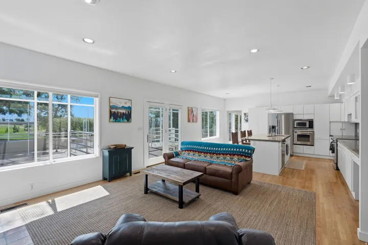 Open-concept living area with wood-finish flooring, recessed lighting, and large windows