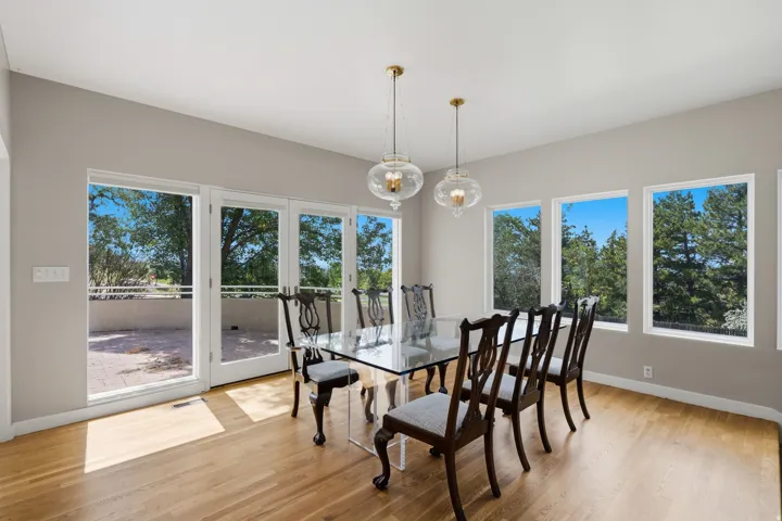 Hardwood-finish flooring with multiple large windows, French doors, and two pendant light fixtures