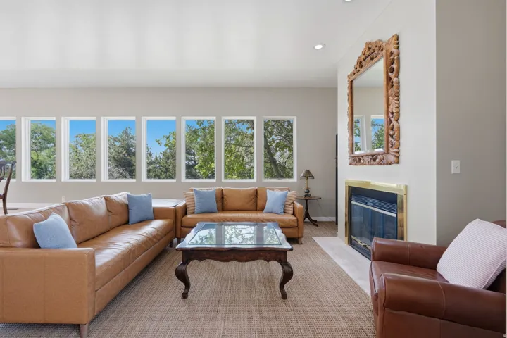 Recessed lighting, a fireplace with a brass-finish trim, and a series of multiple picture windows