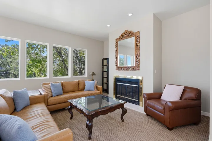 Living area featuring a fireplace with a brass-finish surround, recessed ceiling lighting, and multiple windows