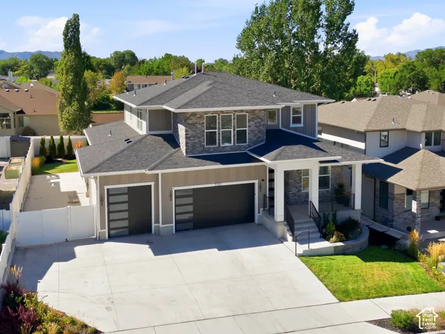 Contemporary exterior featuring stone accents, a multi-paneled garage door, and a covered porch with white columns
