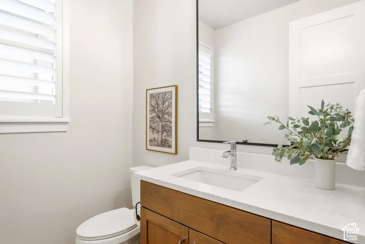 Wood-finish vanity with an undermount sink, chrome faucet, white countertop, and framed mirror