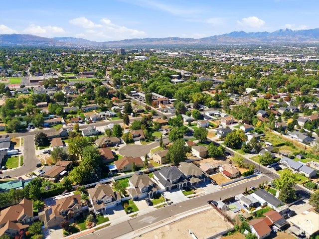 Expansive residential area featuring numerous mature trees, a mix of residential structures, and distant mountains