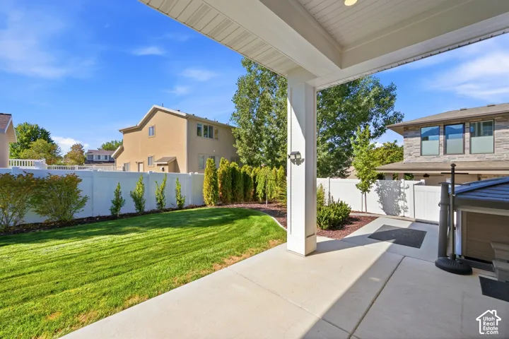 Covered patio area with concrete flooring, recessed lighting, and an expansive lawn