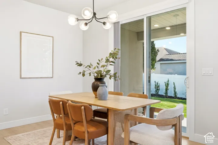 Contemporary chandelier with glass globes, light wood-finish flooring, white walls, and a sliding glass door to exterior