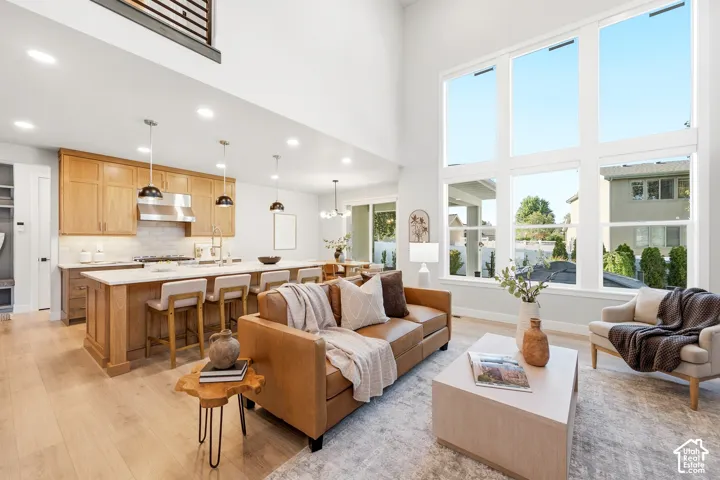 Two-story living area with expansive window wall, wood-finish flooring, and a kitchen featuring a large island with seating, stainless steel appliances, and wood cabinetry