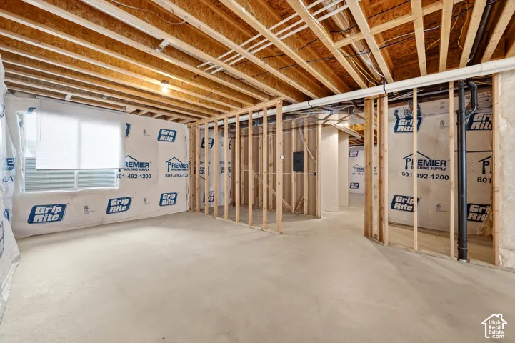 Unfinished basement with exposed wood framing, concrete flooring, and an egress window
