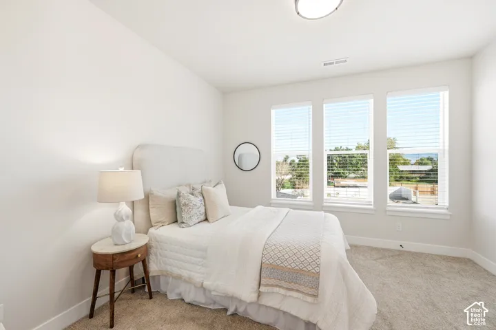 Three large windows with blinds, light wall color, carpeted flooring, and a ceiling-mounted light fixture