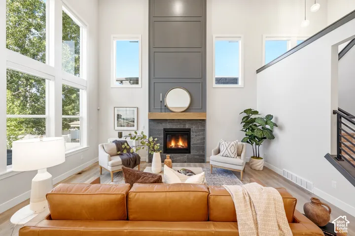 Two-story living area featuring a fireplace with a wood mantle and dark tile surround, vertical paneling, and wood-finish flooring