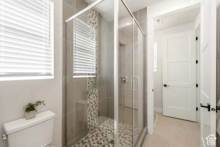Glass-enclosed shower with subway tile surround, hexagonal tile shower pan, and a decorative tile accent strip