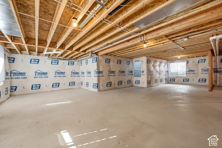 Unfinished basement with exposed ceiling joists and concrete flooring