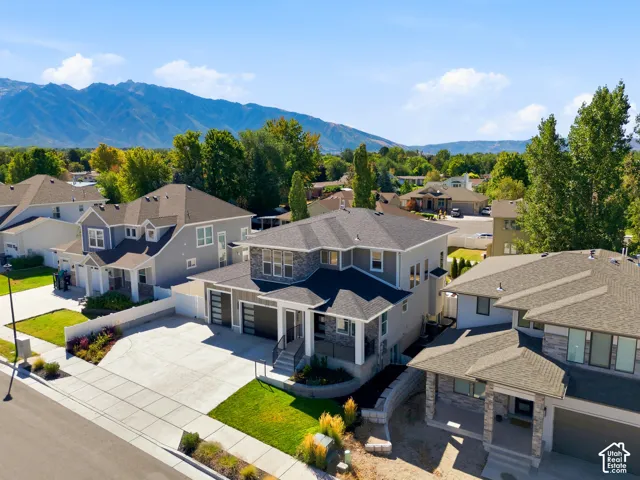 Contemporary exterior with stone accents, a multi-car driveway, mature landscaping, and mountain scenery