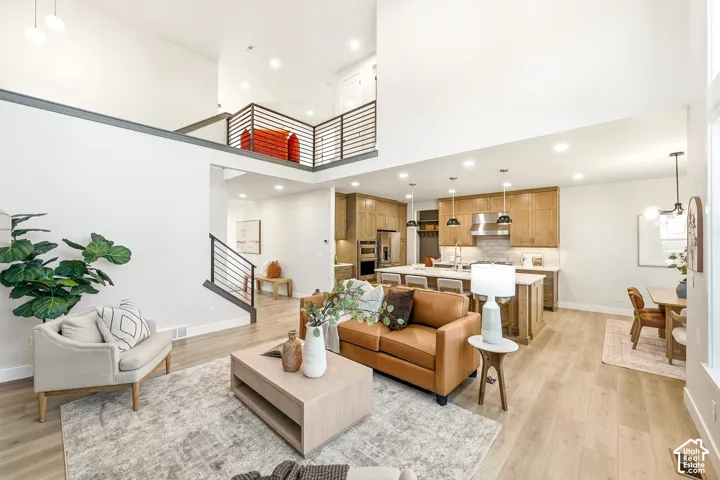 Two-story living area with high ceilings, light wood-finish flooring, and a modern kitchen featuring wood cabinetry