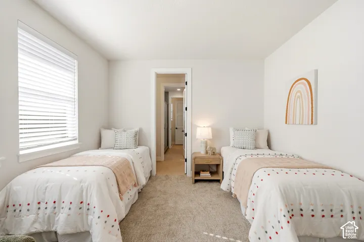 Plush carpet flooring, a window with blinds, and white walls