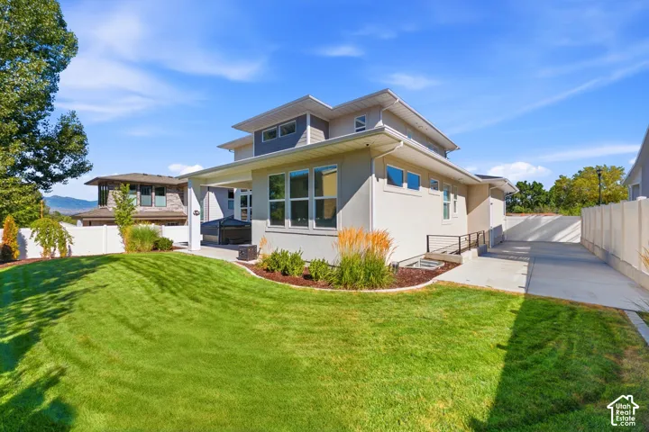 Expansive backyard featuring a manicured lawn, an outdoor patio, and mature landscaping