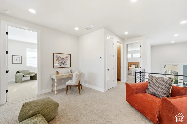Recessed lighting, light-toned carpeting, white interior doors, and a black metal railing