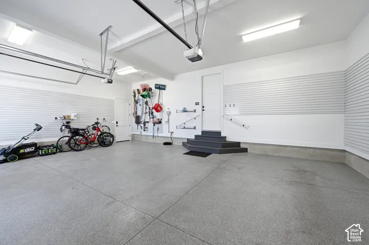 Epoxy-coated flooring, white slatwall paneling, built-in shelving, white interior door, and overhead lighting fixtures