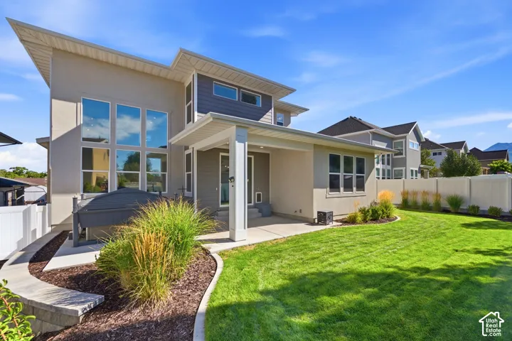 Expansive backyard featuring a manicured lawn, established landscaping, and a privacy fence