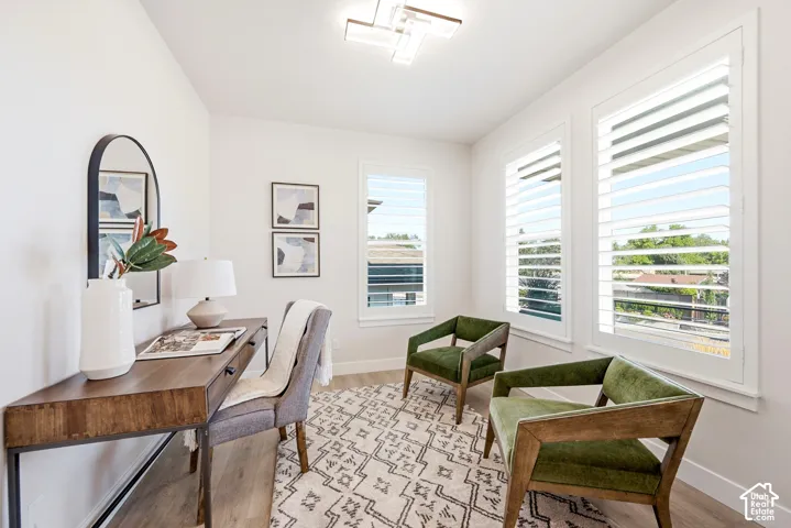 Wood-finish flooring, white plantation shutters, white walls, and a contemporary ceiling light fixture