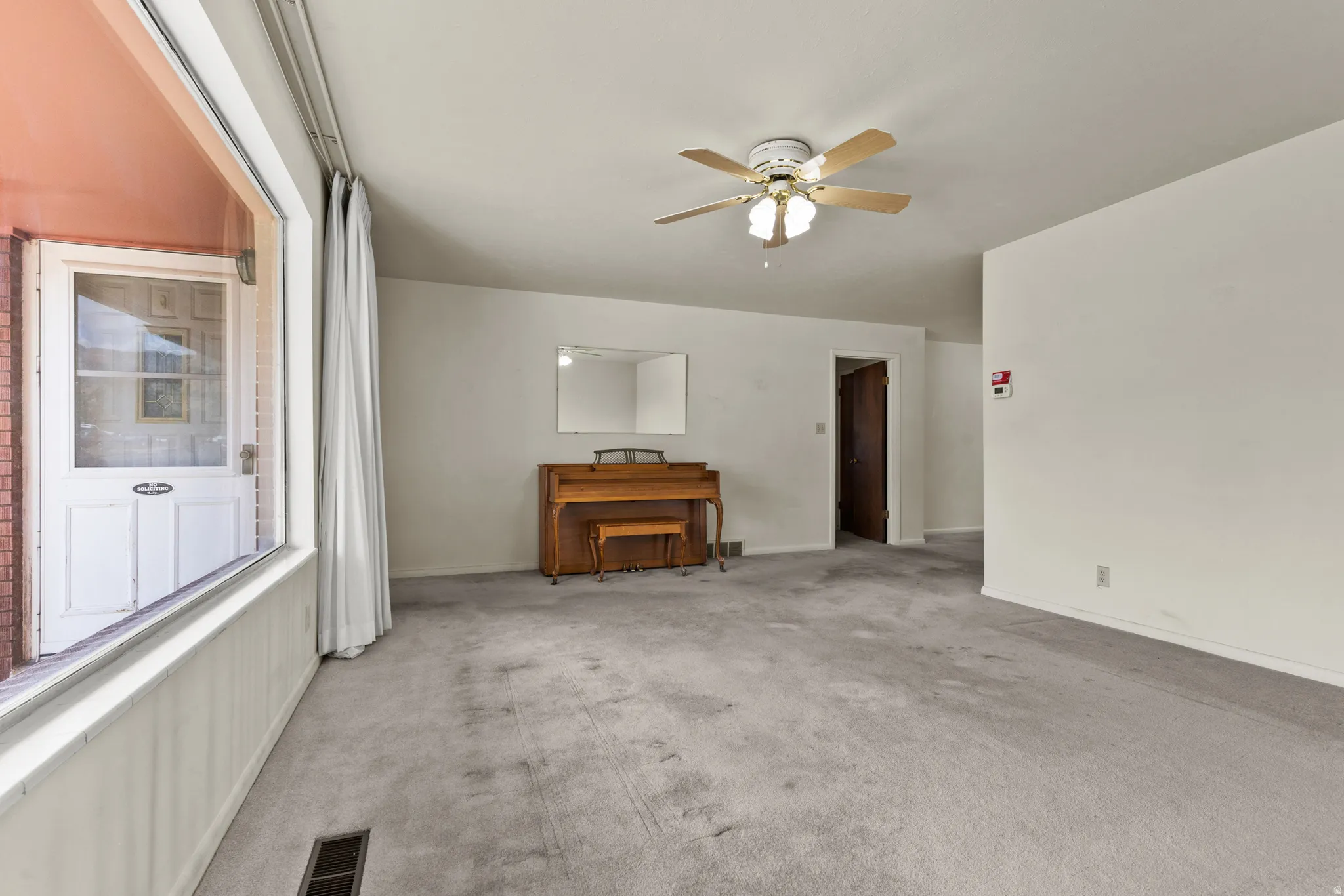Broadloom carpeting, ceiling fan with integrated lighting, and a large window with white trim