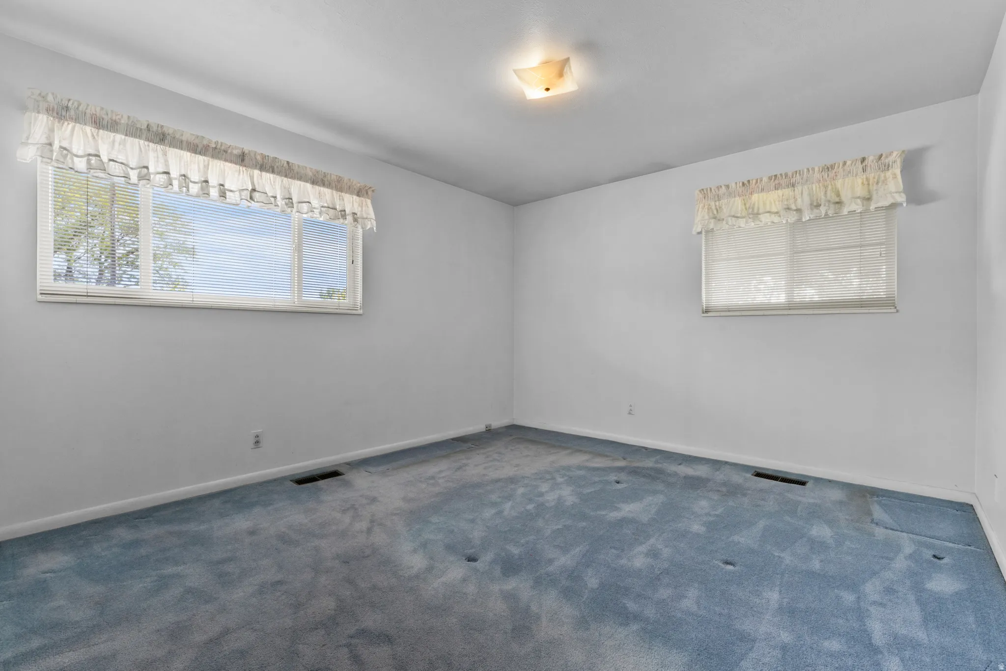 Bright corner bedroom with dual windows featuring natural light, neutral wall finishes, and carpet flooring