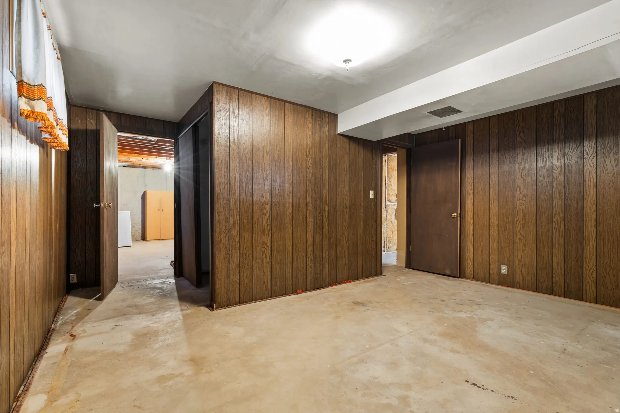 Expansive open floor plan with rich wood-paneled walls, concrete flooring, and recessed ceiling lighting