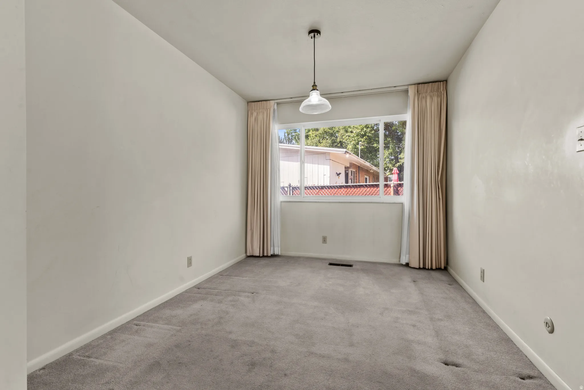 Bright corner room flooded with natural light through expansive windows dressed with neutral curtains