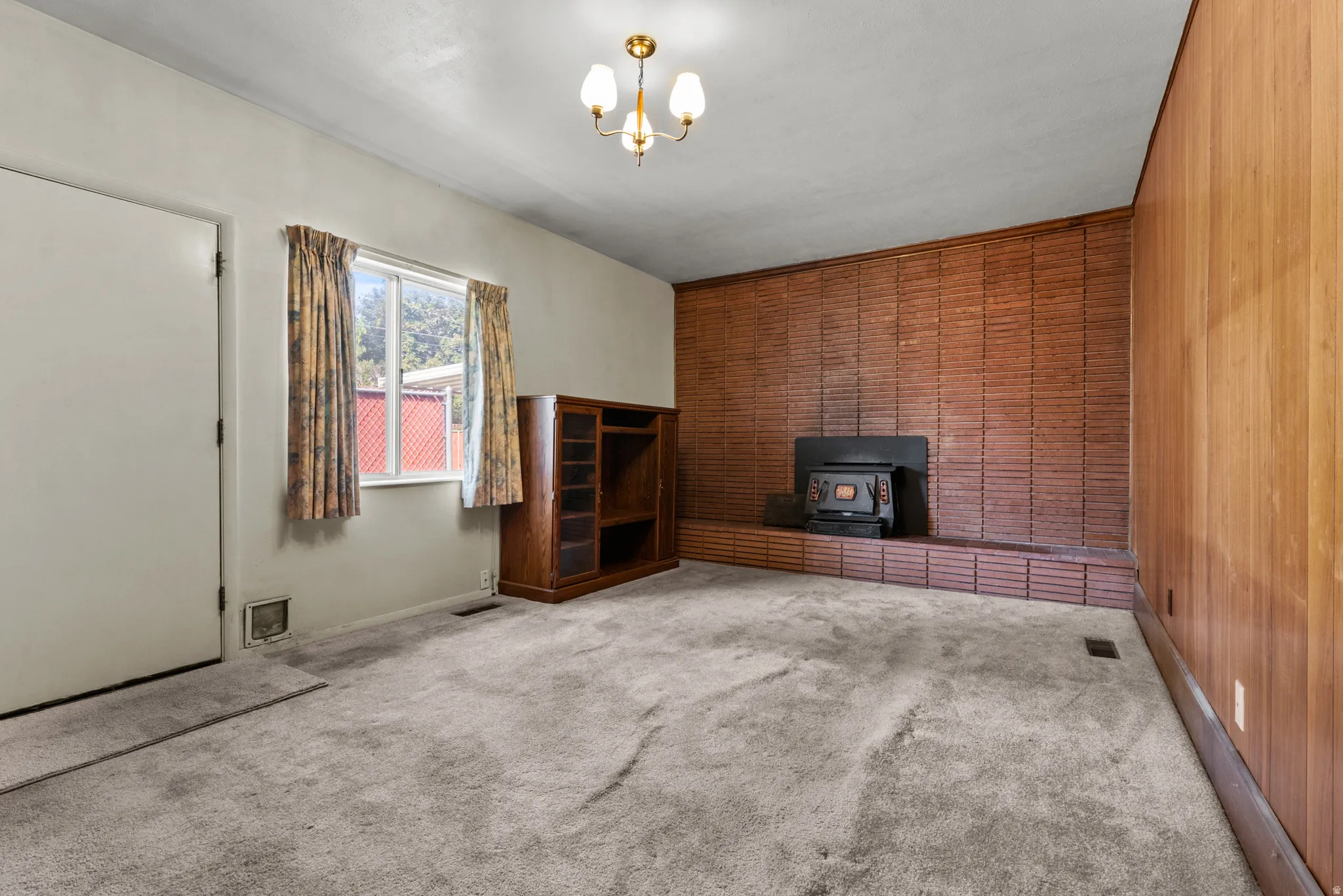 Spacious room featuring rich wood-paneled walls, neutral carpet flooring, and built-in wood cabinetry
