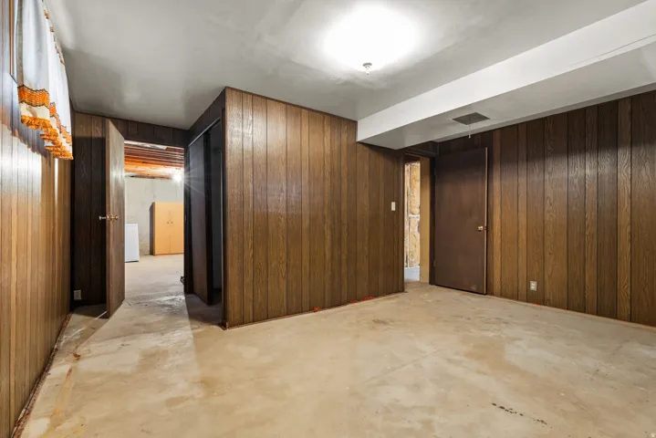 Expansive open floor plan with rich wood-paneled walls, concrete flooring, and recessed ceiling lighting