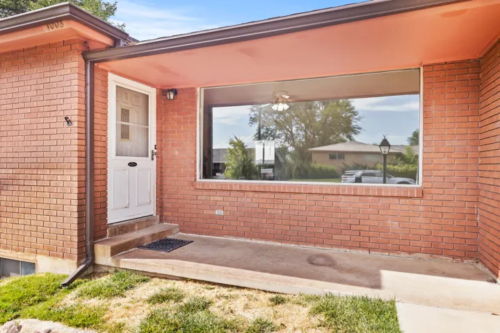 Brick exterior with a large picture window, covered entryway, concrete porch, and white paneled door