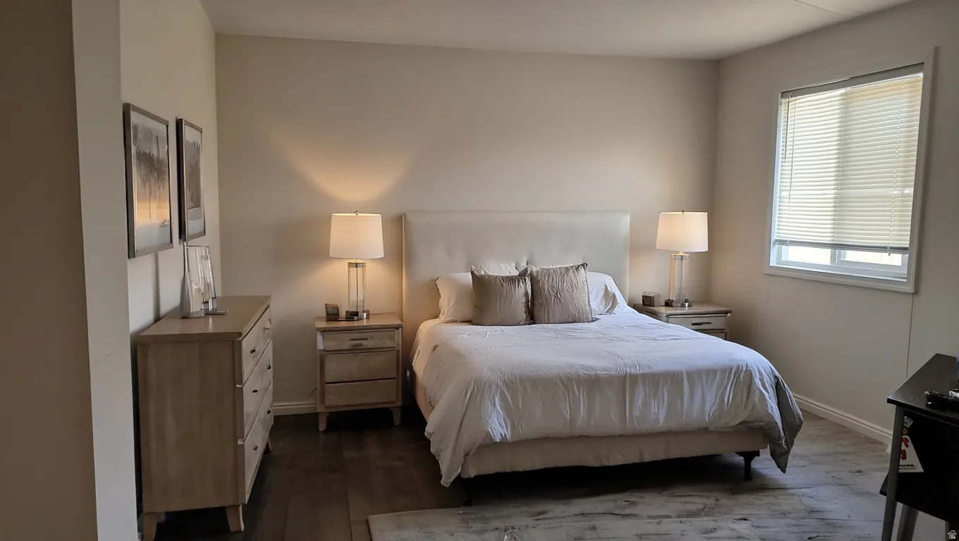Spacious room featuring wood-finish flooring, a large window with blinds, and neutral wall tones